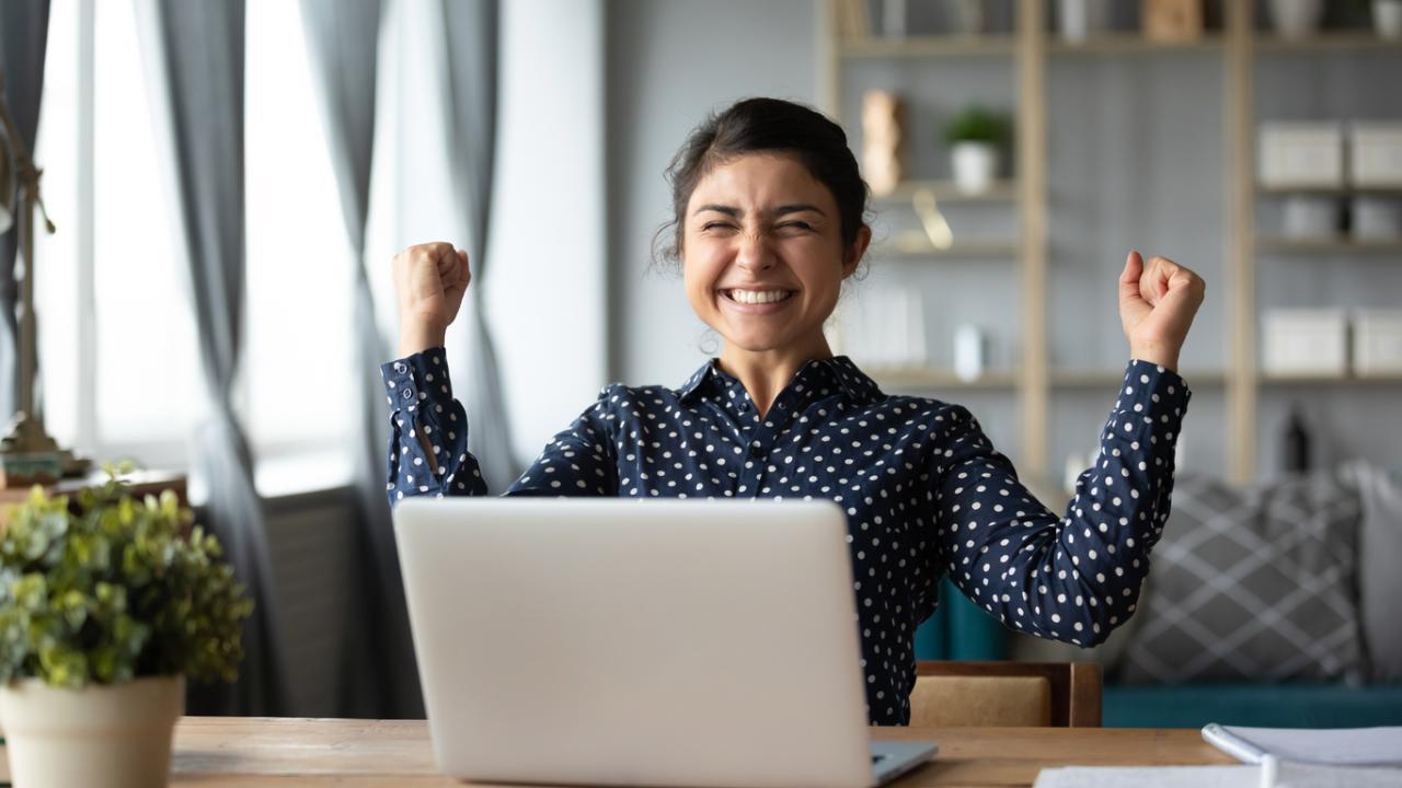 Excited woman sitting in front of laptop computer