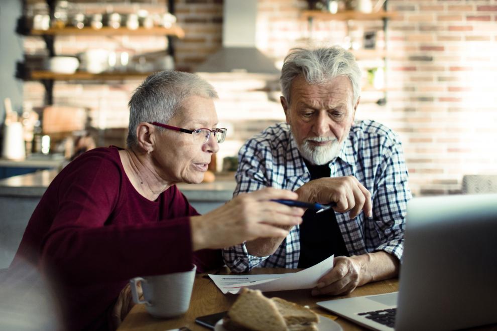senior couple having breakfast while doing bills and using their laptop